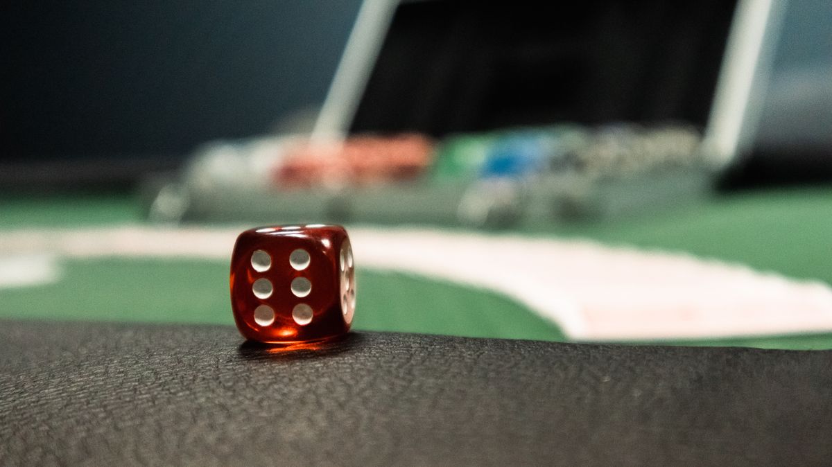 Dadu merah dengan chip poker di meja kasino gelap